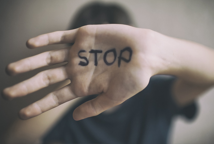Image of teen with hand blocking their face and STOP written on their hand.